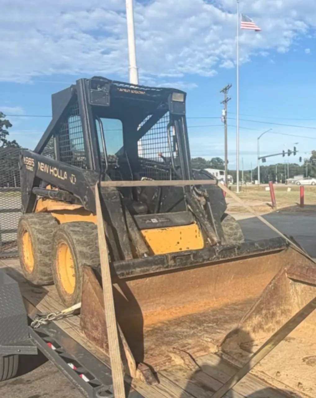 Front view of a New Holland skid steer behind a landscaping bucket