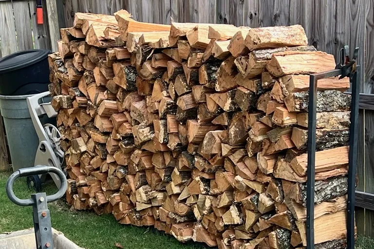 Large stack of split hardwood firewood stored in an outdoor rack